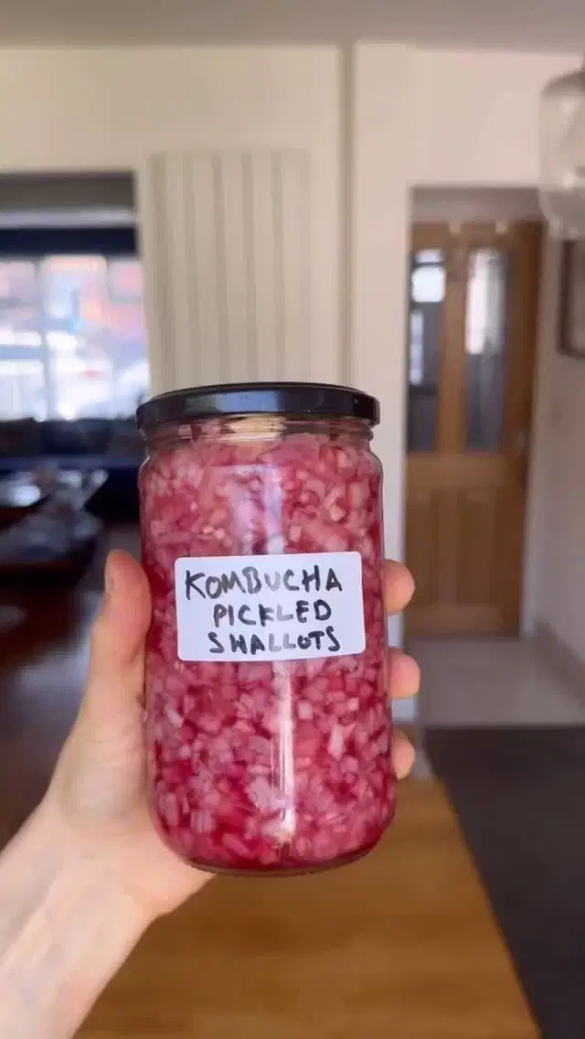 I always have something pickling in my fridge – it’s such a simple way to add brightness and balance to meals. A quick pickle is endlessly versatile, ready to be tossed onto a taco, spooned over a grain bowl, or added to a sandwich for that extra tang and crunch. It keeps well, takes minutes to make, and instantly brings life to whatever you’re cooking.Thanks to the @herbamareuk herb sea salt which adds so much flavour to this pickle Spiced Kombucha Shallots 300g Shallots (unpeeled)50g Caster Sugar 250ml Kombucha ½ tbsp @herbamareuk Herb Sea Salt 1 Cinnamon stick 1-2 sliced Fresh Ginger¼ tsp Dried Chilli Flakes Bay Leaves to top with Thinly dice the shallots and add top the jar. To make the brine add the sugar, kombucha, salt and spices and to pan and bring to a gentle simmer until the sugar has dissolved. When the brine has cooled slightly pour it over the shallots. Use overlapping bay leaves, a vine leaf or square of a clean cloth to cap the shallots and hold them under the brine. Allow the mixture to pickle in the fridge and it is ready to eat after 24 hours. #seasonalcooking #pickle #pickledshallots #kombucha #condiment #guthealth
